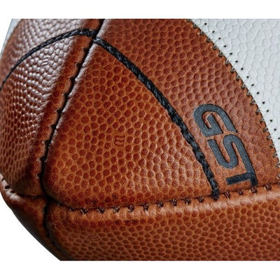 Close-up of brown Wilson GST Prime football showing detailed pebble texture, black stitching, and GST logo on composite stripe